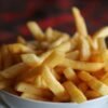 Delicious crispy golden french fries served in a white bowl, perfect for a tasty snack.