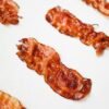 High-quality food photography of crispy bacon slices arranged on a white background.
