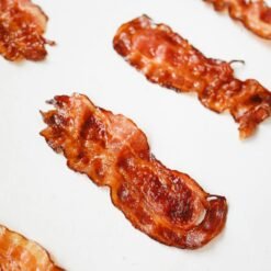 High-quality food photography of crispy bacon slices arranged on a white background.